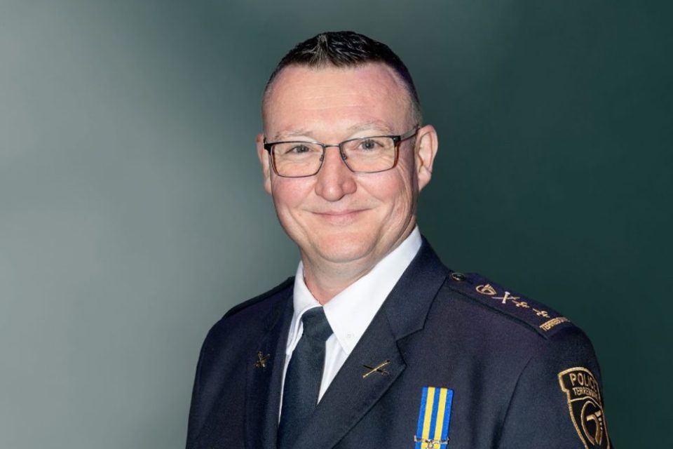 Benoît Bilodeau en uniforme officiel, avec insignes et médailles, posé devant un fond uni vert.