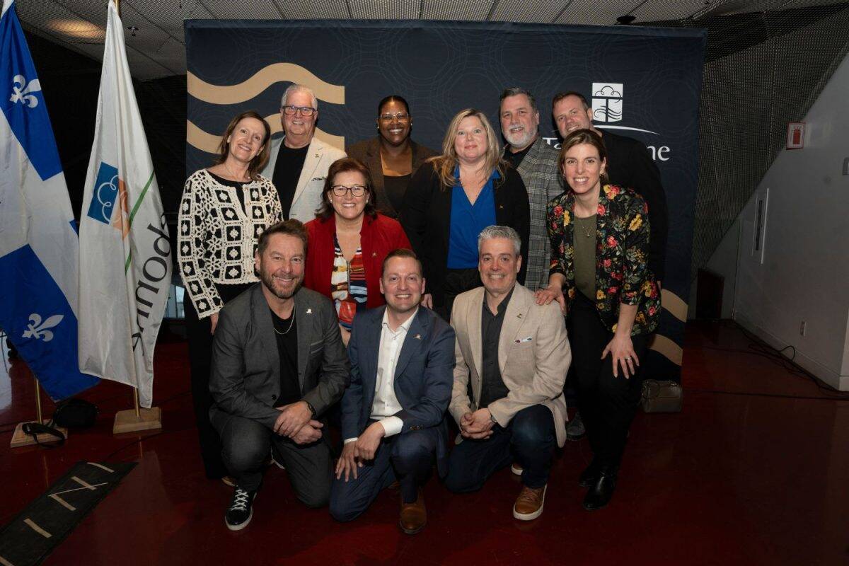 Groupe de représentants officiels posant devant drapeau devant toile de fond événementielle