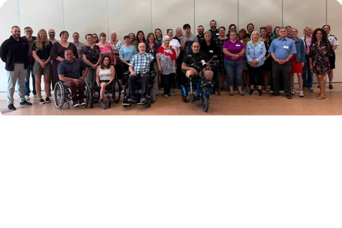 Groupe de trente personnes posant ensemble dans une salle lors d'une réunion communautaire inclusive