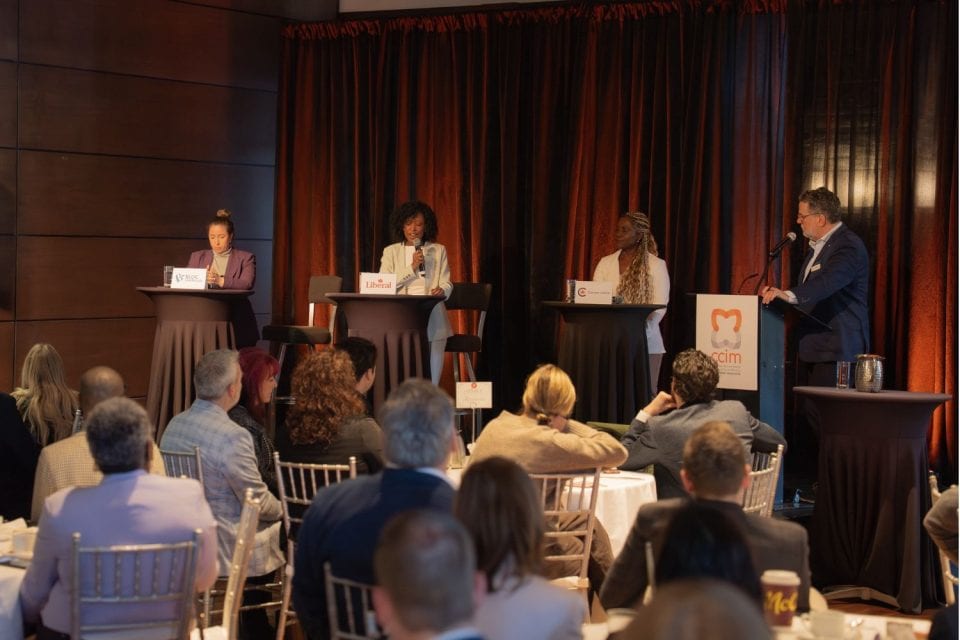 Dix personnes posent devant bannière d'organisation CCIM dans salle d'événement avec drapeaux québécois