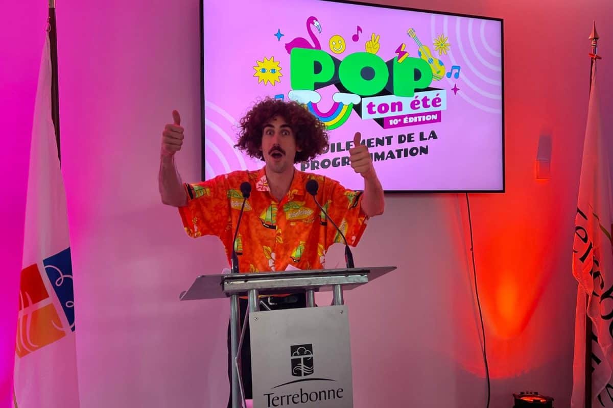 Un présentateur enthousiaste avec les bras levés sur scène lors d'un festival musical très coloré