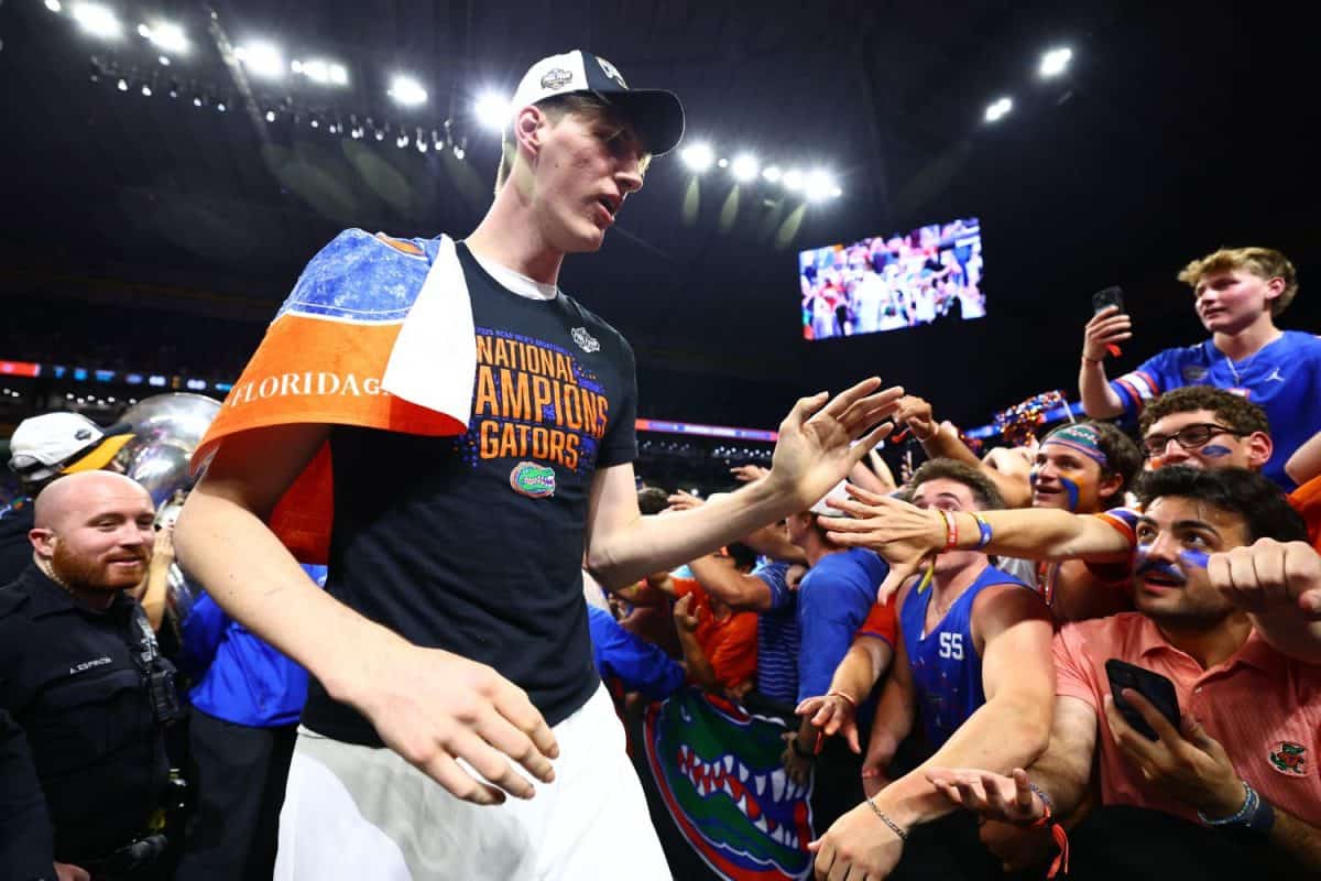 Un athlète célèbre une victoire entouré de nombreux fans dans un stade illuminé par les projecteurs