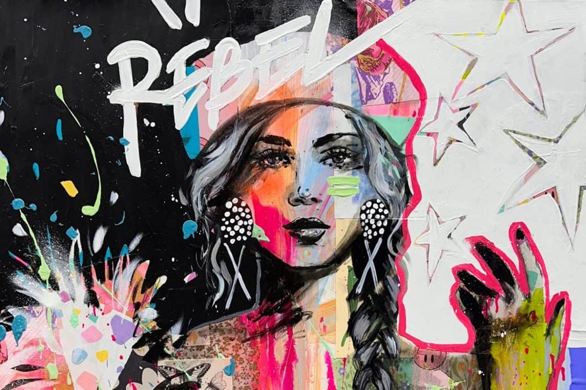 Œuvre d'art urbain aux couleurs vives représentant un visage stylisé avec le mot REBEL et des étoiles sur fond noir et rose