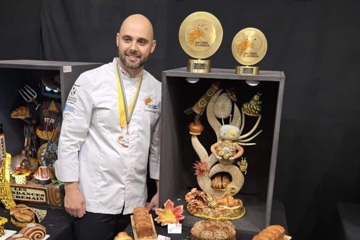 Boulanger médaillé posant devant un présentoir de créations artistiques en pain lors de la Coupe du Monde de la Viennoiserie