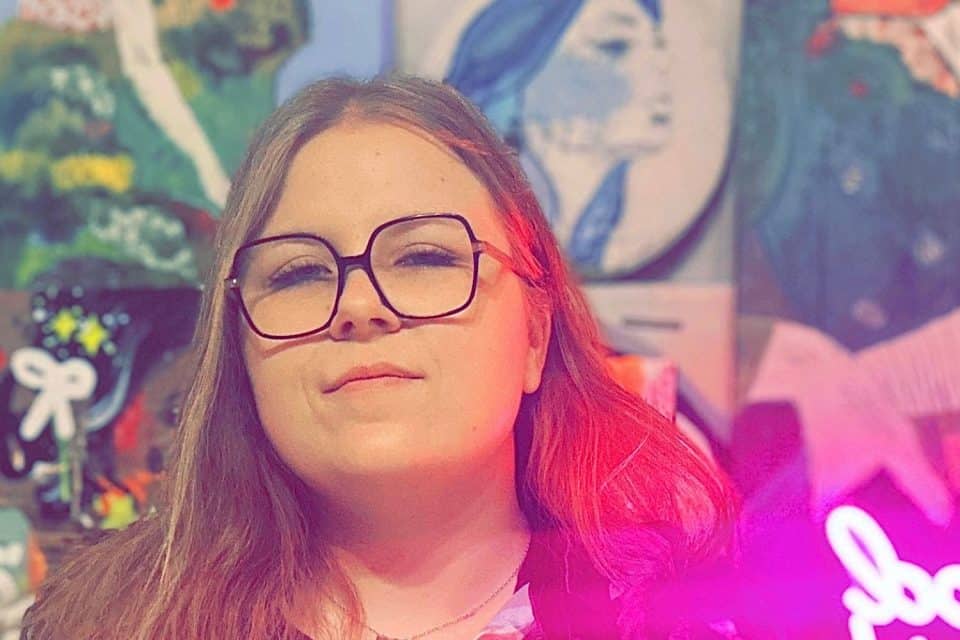 Portrait devant un mur couvert de peintures murales colorées et d'une enseigne néon rose dans un espace artistique