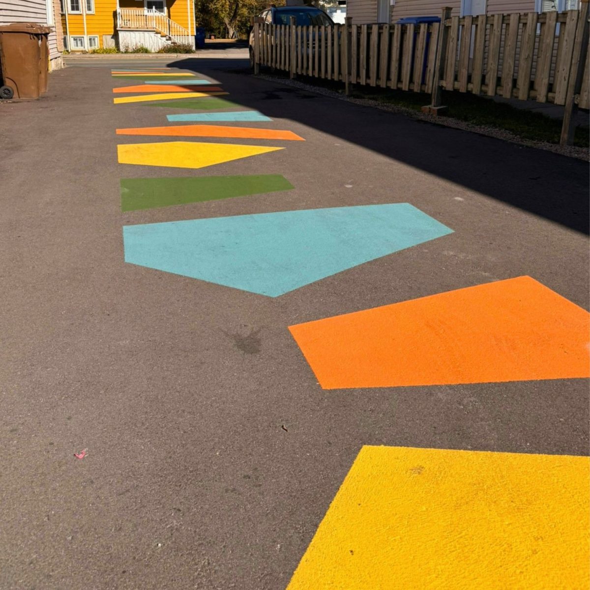 Œuvre d'art public aux formes géométriques colorées peintes sur l'asphalte d'une ruelle du Vieux-Mascouche