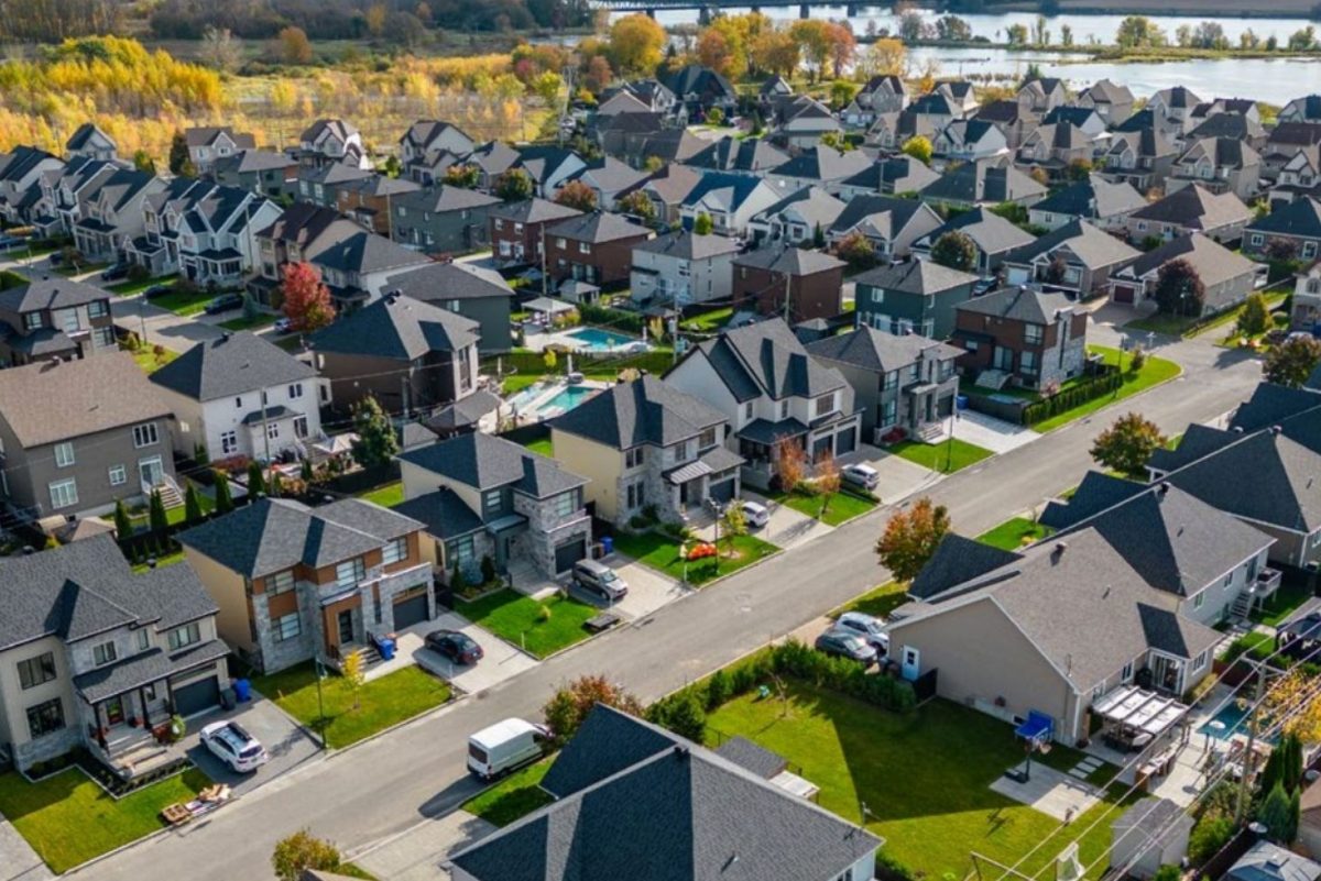 Vue aérienne d'un quartier résidentiel de Terrebonne, maisons en rangées serrées et cours verdoyantes, rivière en arrière-plan
