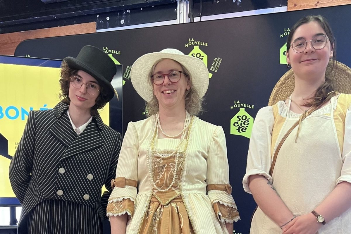 Trois comédiens en costumes d'époque devant la bannière de La Nouvelle Société, lors du lancement de la programmation estivale