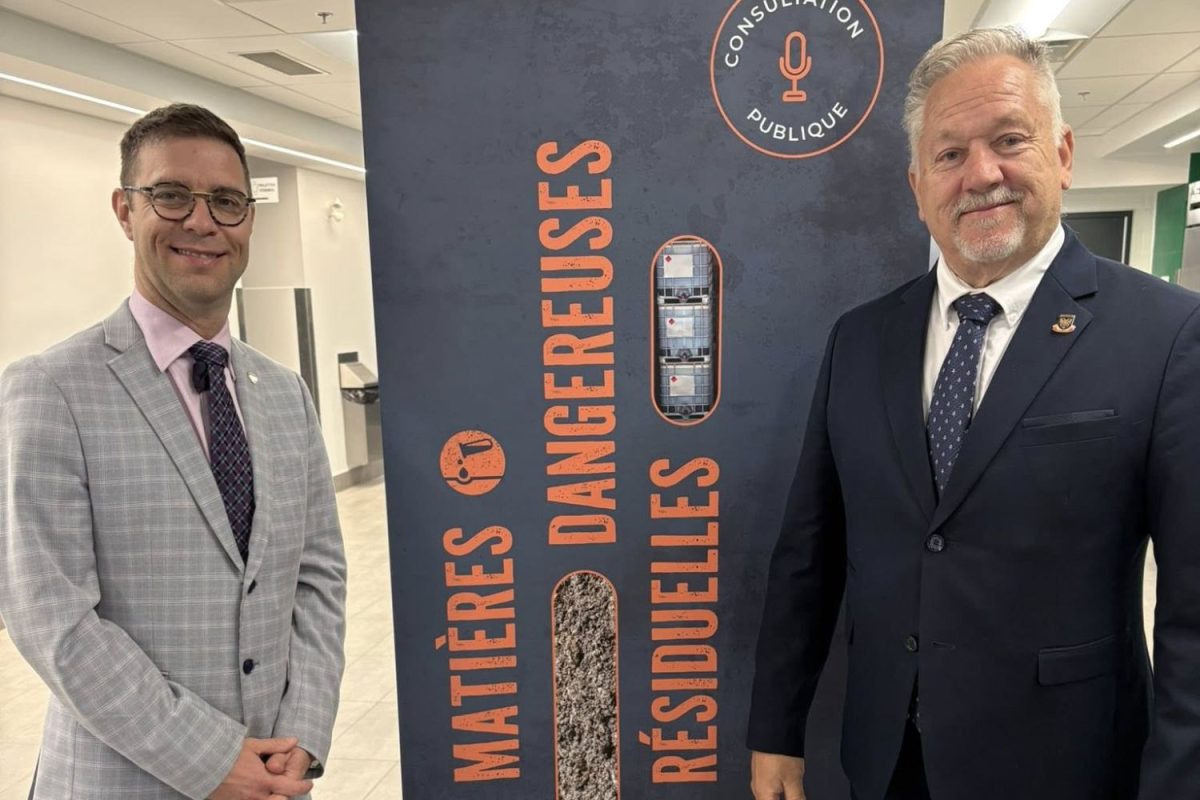 Deux représentants devant la bannière de consultation publique sur les matières dangereuses résiduelles de la MRC Les Moulins