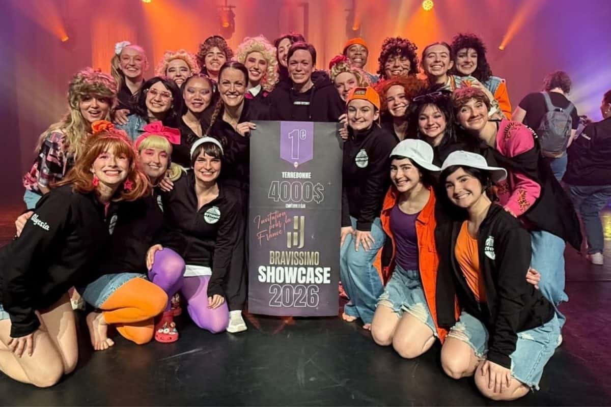 Troupe de danse tenant une bannière de première place sur scène sombre lors de la compétition Bravissimo 2026