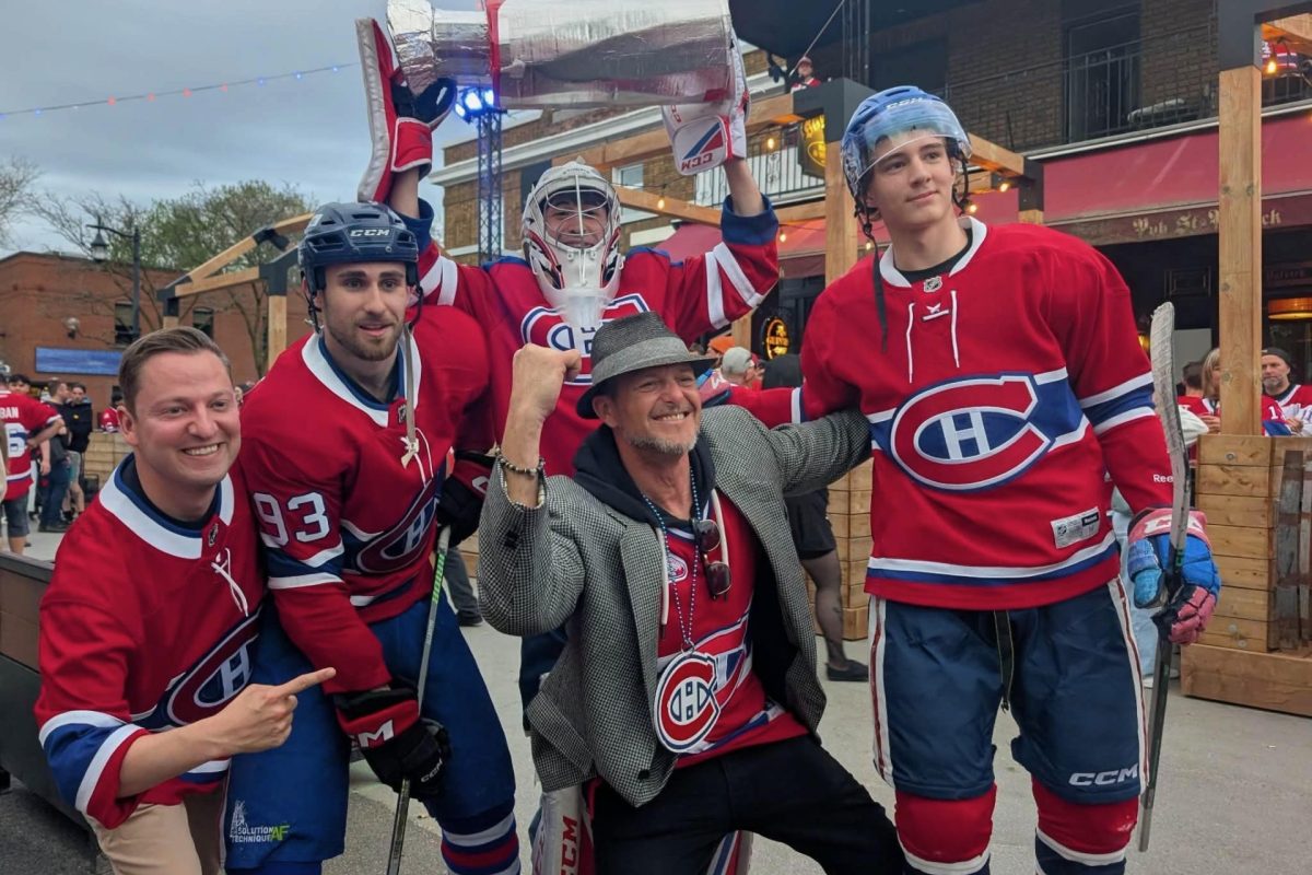 Groupe de partisans et joueurs en chandails des Canadiens de Montréal célébrant dans une rue animée avec une coupe géante.
