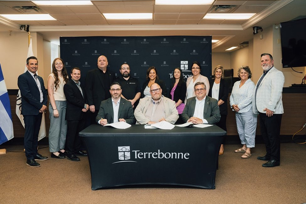 Signature officielle d'une convention collective dans la salle du conseil de Terrebonne, signataires attablés et témoins