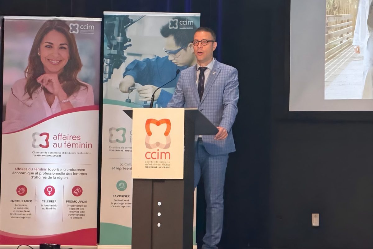 Conférencier au podium de la Chambre de commerce devant des bannières lors d'un dîner-conférence sur une scène