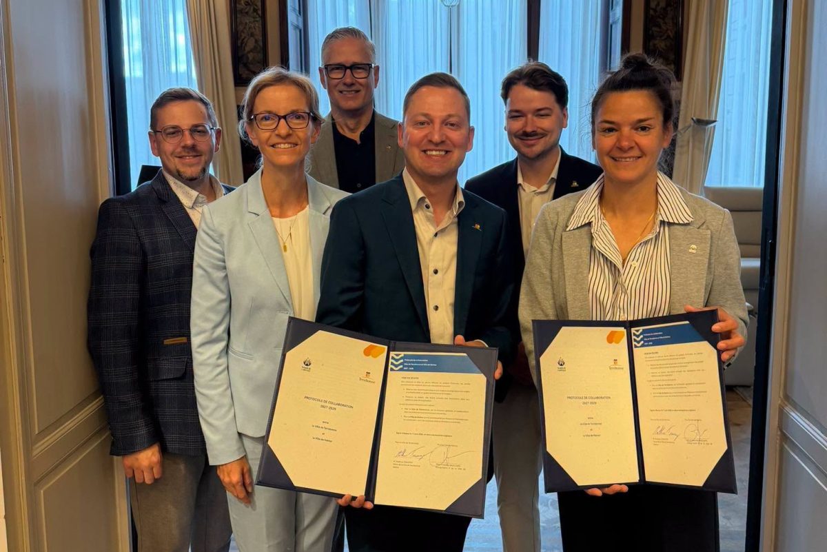 Groupe de six personnes posant dans une salle lumineuse, tenant deux protocoles de collaboration 2027-2029 ouverts face caméra
